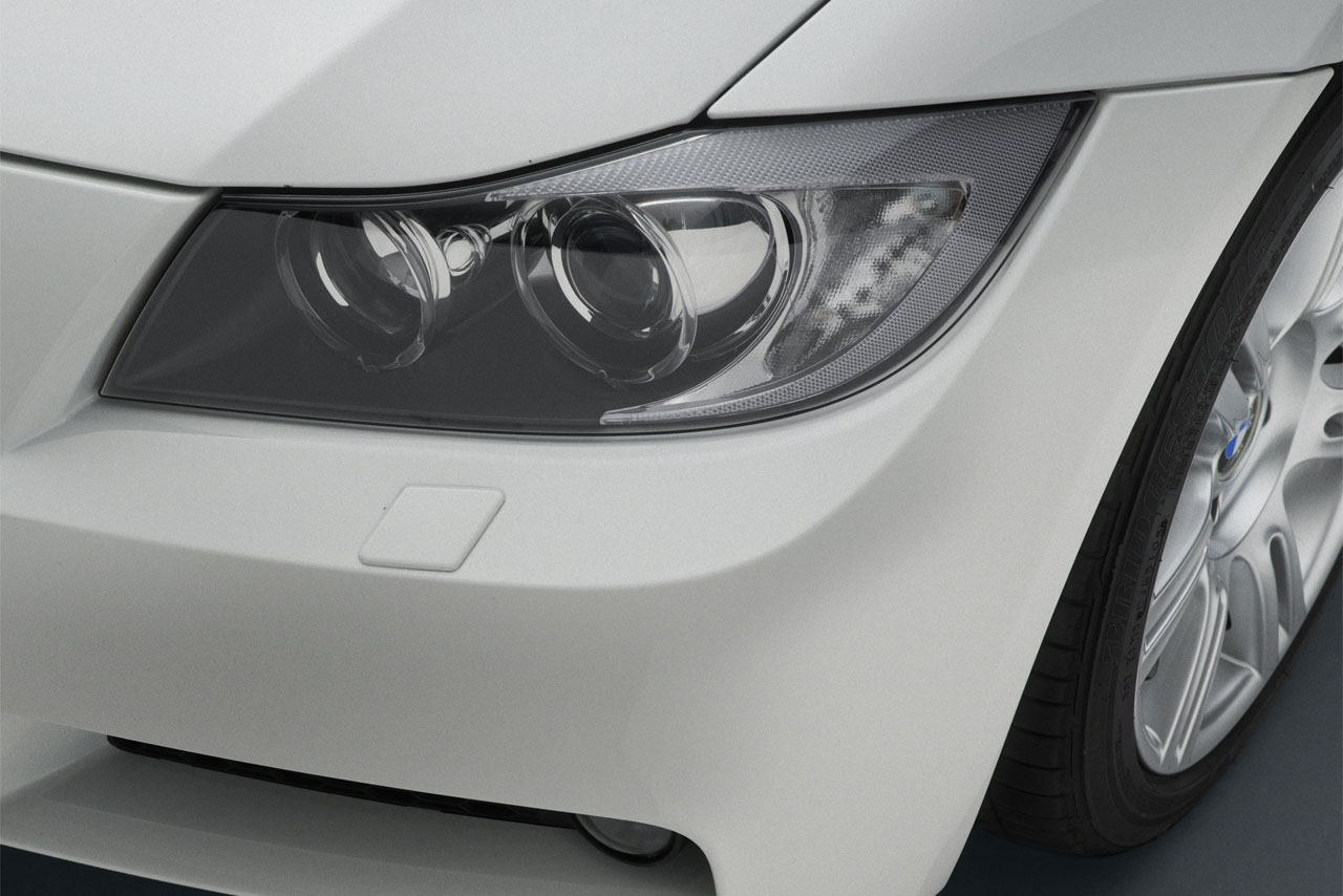 A white E91 Touring: A closeup from above of the left-hand headlight.