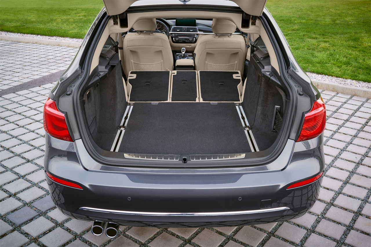 View through the open tailgate into the cargo area of a dark grey BMW F34 Gran Turismo. The rear seats are folded down.