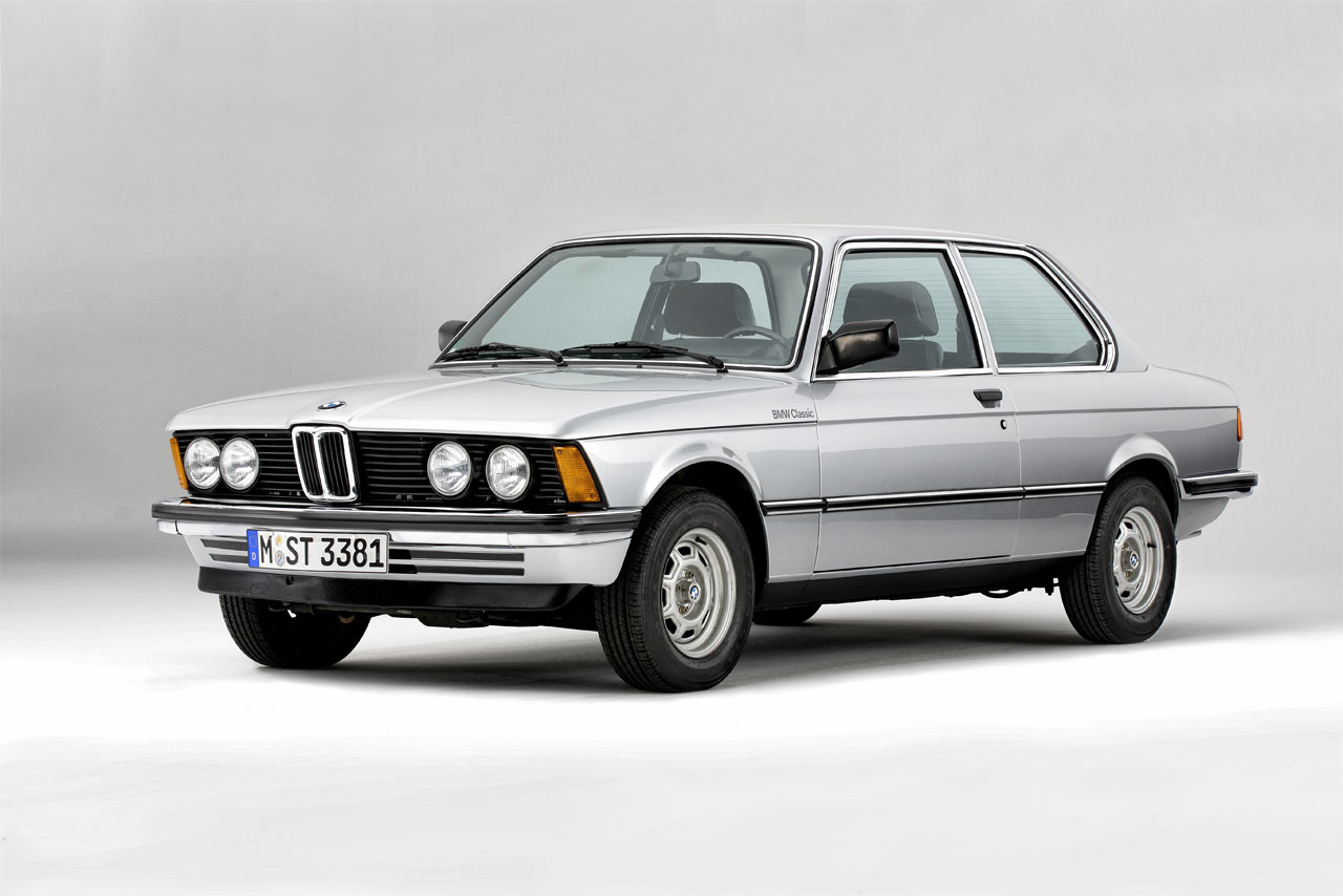 A silver BMW E21 with double headlights – viewed from the front left.
