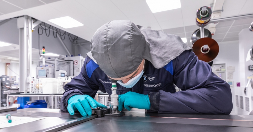 A person in a workshop environment is bent over a microscope placed on a table.