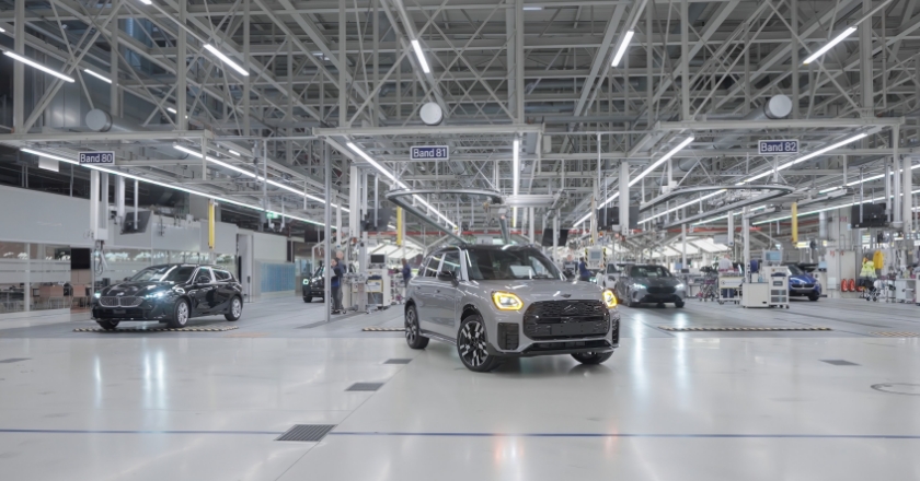 Grey, driverless MINI vehicle is driving through a factory hall.