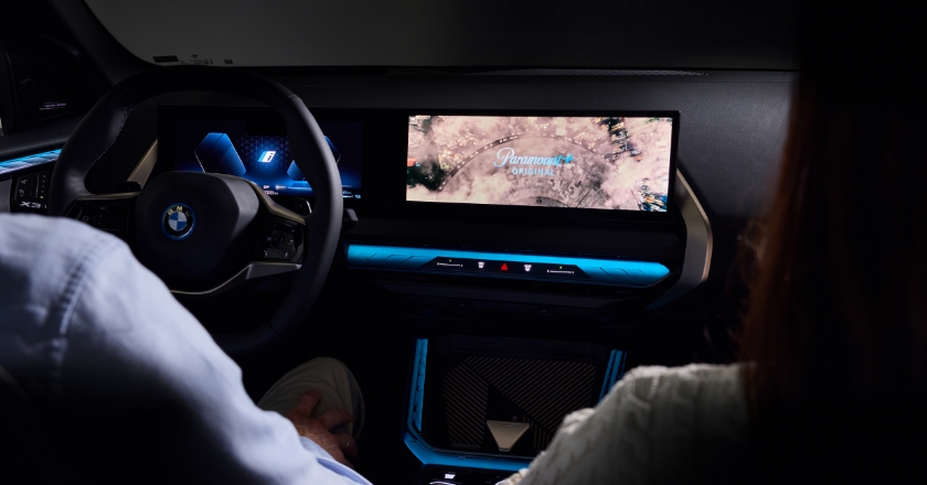 Two passengers are sitting in a BMW. In front of them is a large display that reads “Paramount Original”.