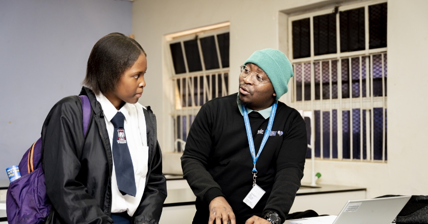 Two people, one of them in school uniform, are talking.