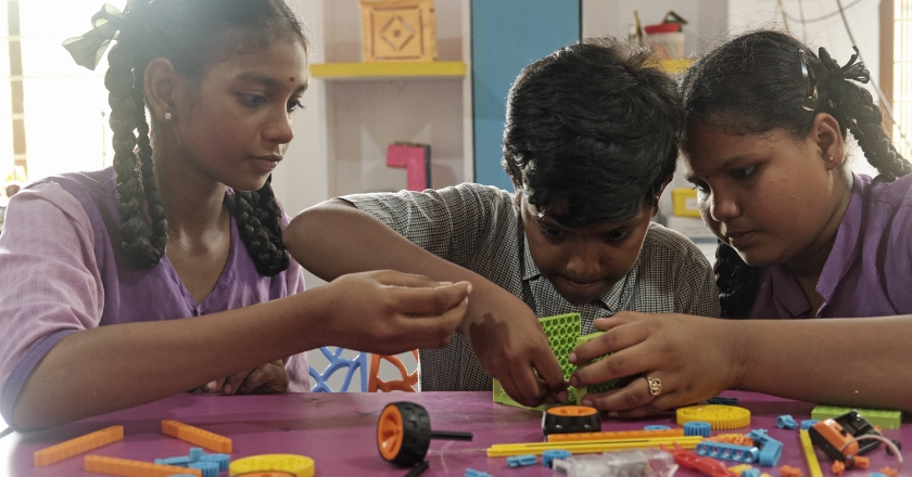Schoolchildren work together to build a model from plug-in toys.