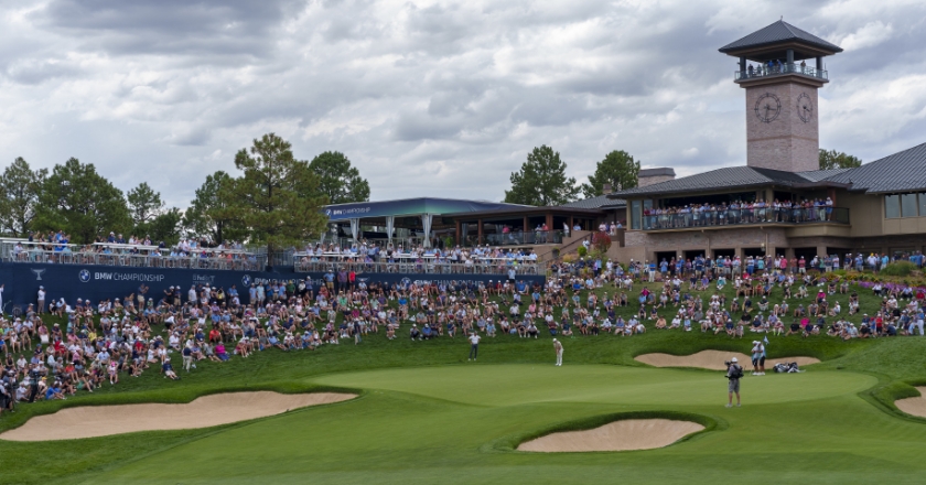 A large crowd of spectators watches a golf tournament.