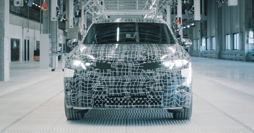 The front of a black BMW vehicle with camouflage foil in a factory.