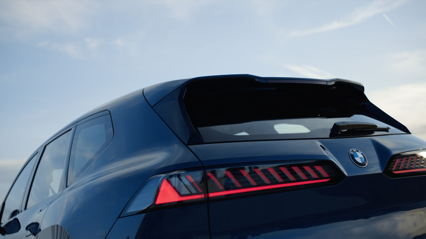 Rear of a BMW with distinctive tail lights against a bright sky.