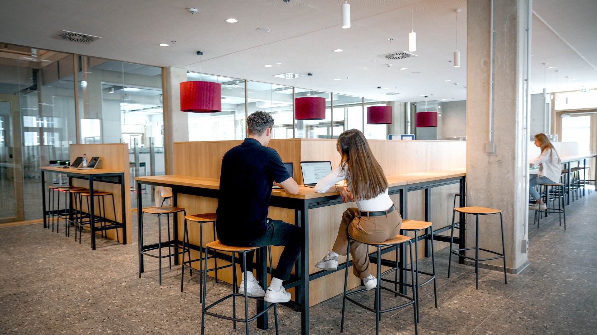 People working in an open office area with high tables and modern wooden elements.