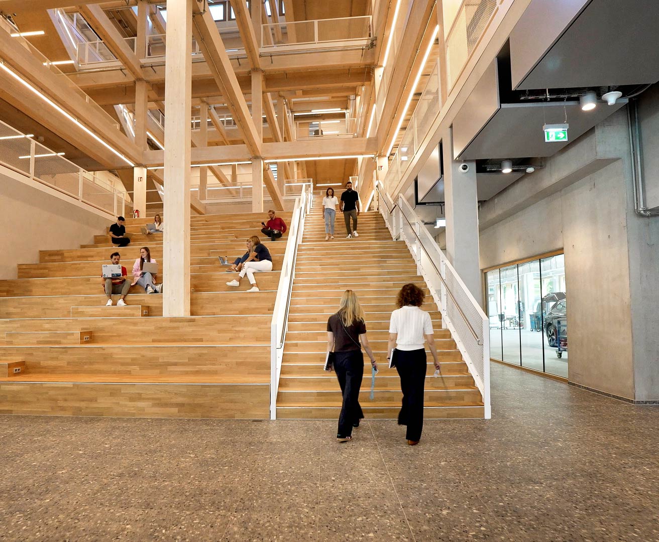 Large staircase and seating area in a modern building, with several people using the steps for working or walking.