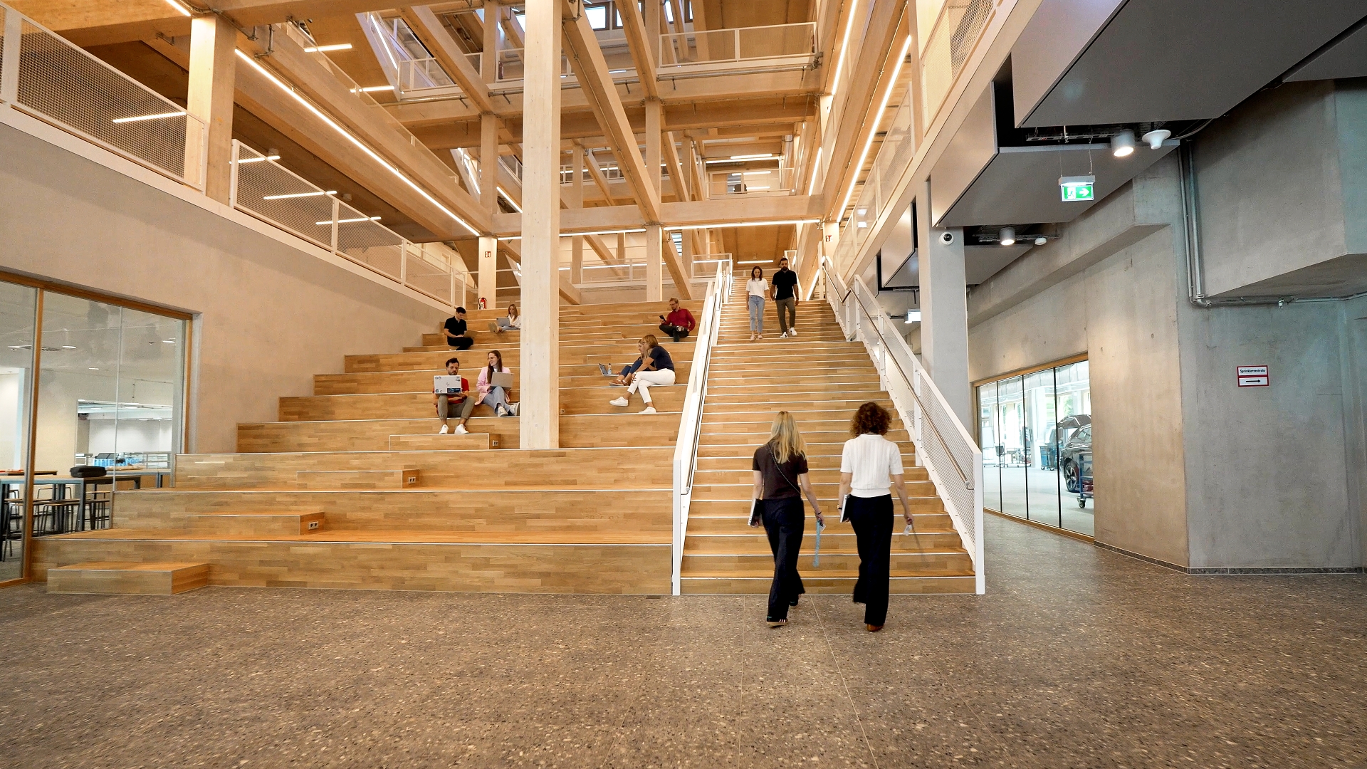 Large staircase and seating area in a modern building, with several people using the steps for working or walking.