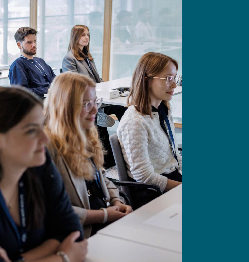 People sitting at tables in a bright training room, following a presentation or instructional session.