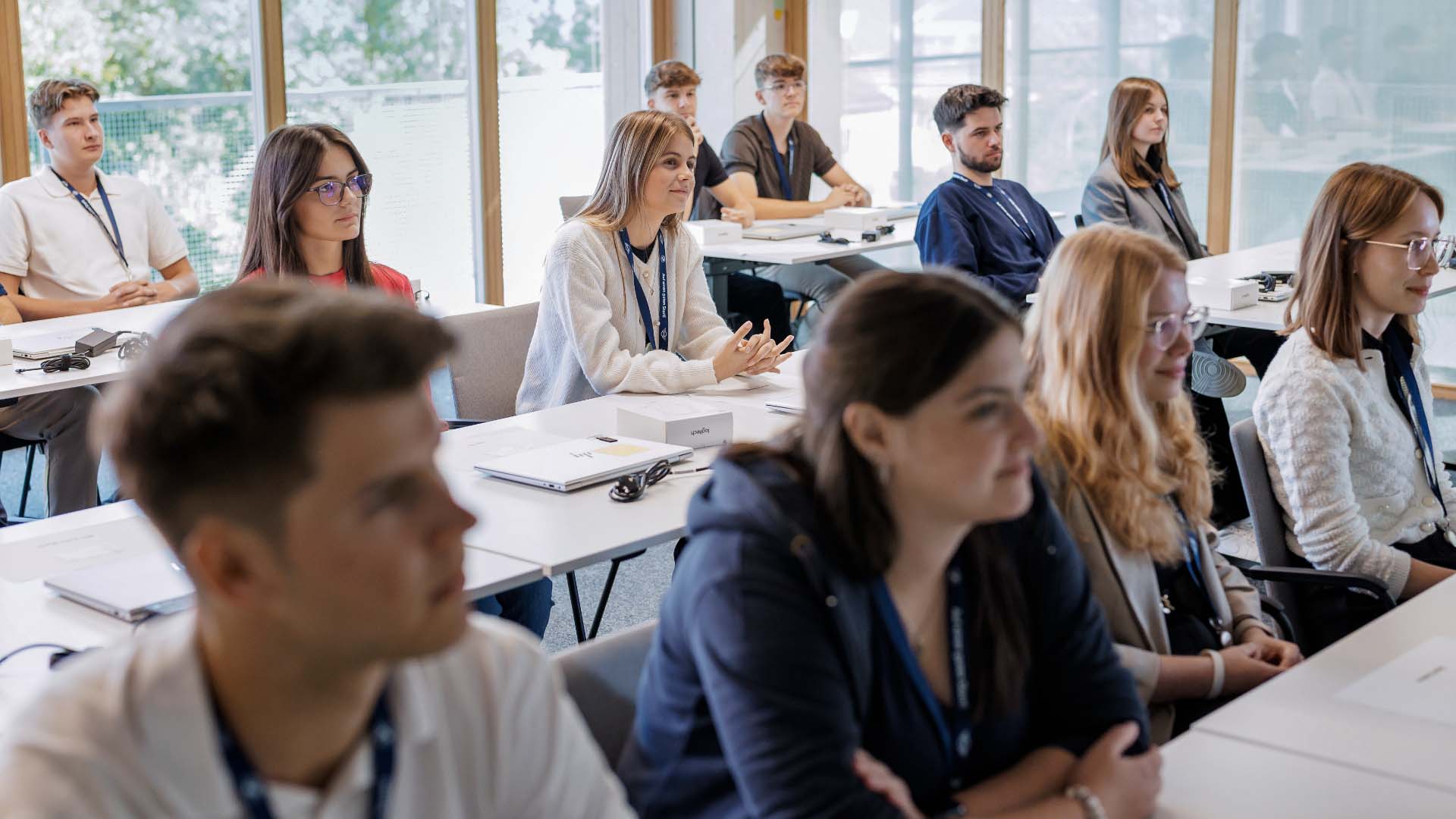 People sitting at tables in a bright training room, following a presentation or instructional session.