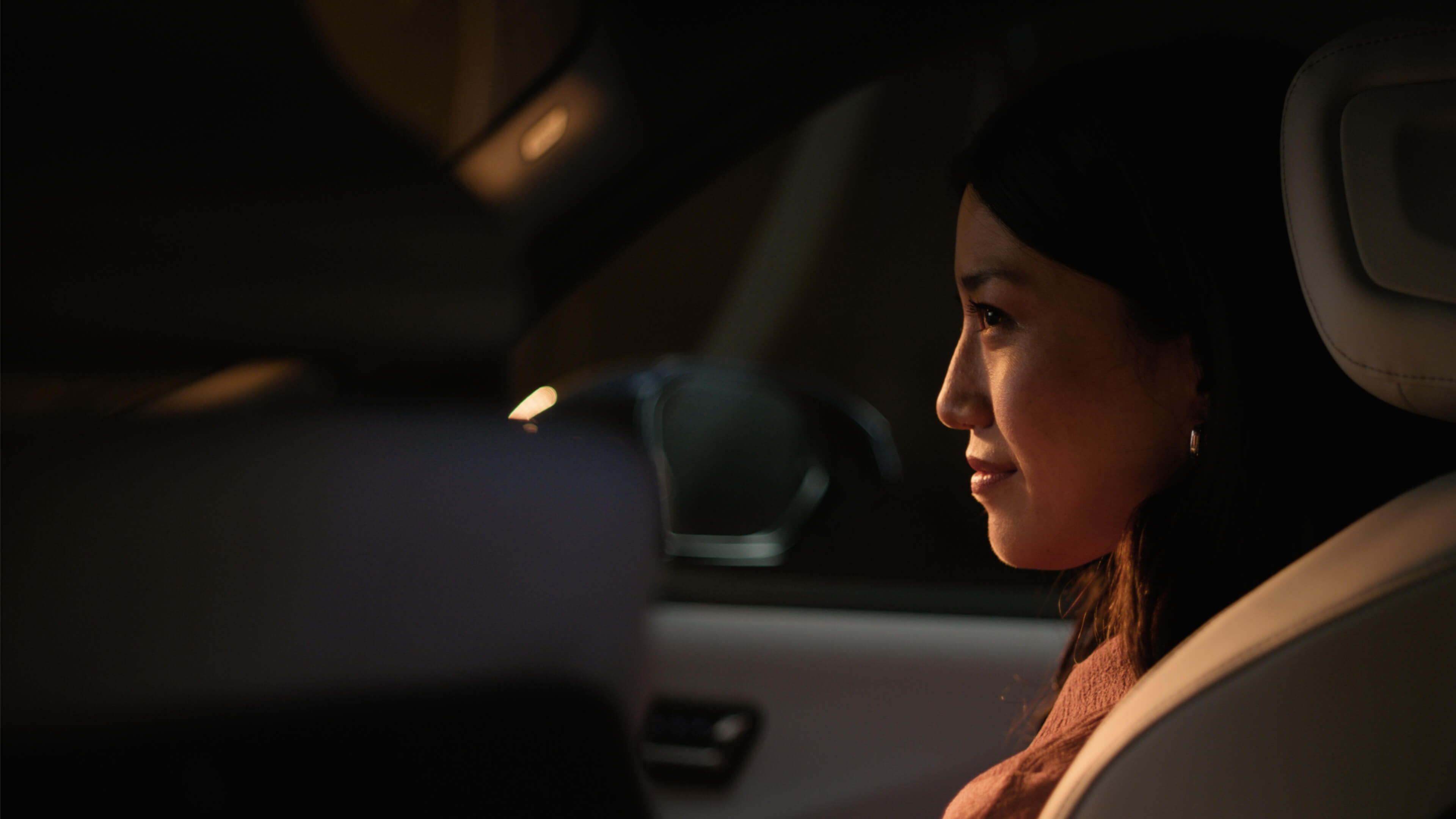 Person in the front passenger seat, side‑lit by warm interior lighting.