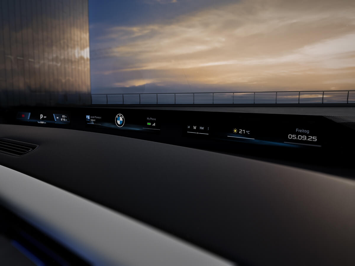 Digital BMW panoramic vision display in the cockpit showing weather, navigation details and vehicle information with a bright sky in the background.