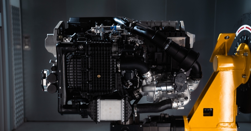 Powertrain unit is mounted on a yellow support structure and displayed in an isolated technical setting.