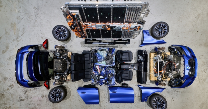 Disassembled BMW vehicle laid out in individual components, including body parts, interior and drivetrain unit.