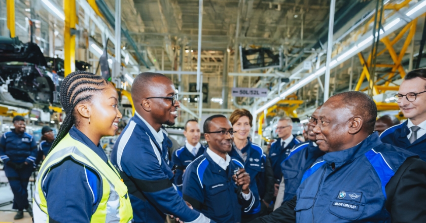 Employees in a BMW production line, with two people shaking hands.