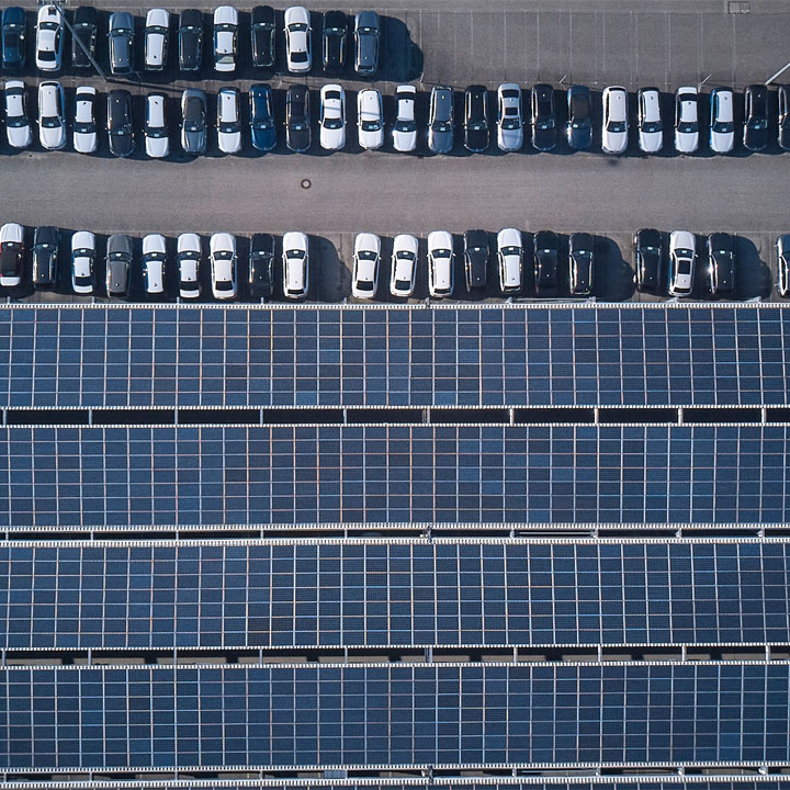 Aerial view of a parking lot with rows of white and blue cars.