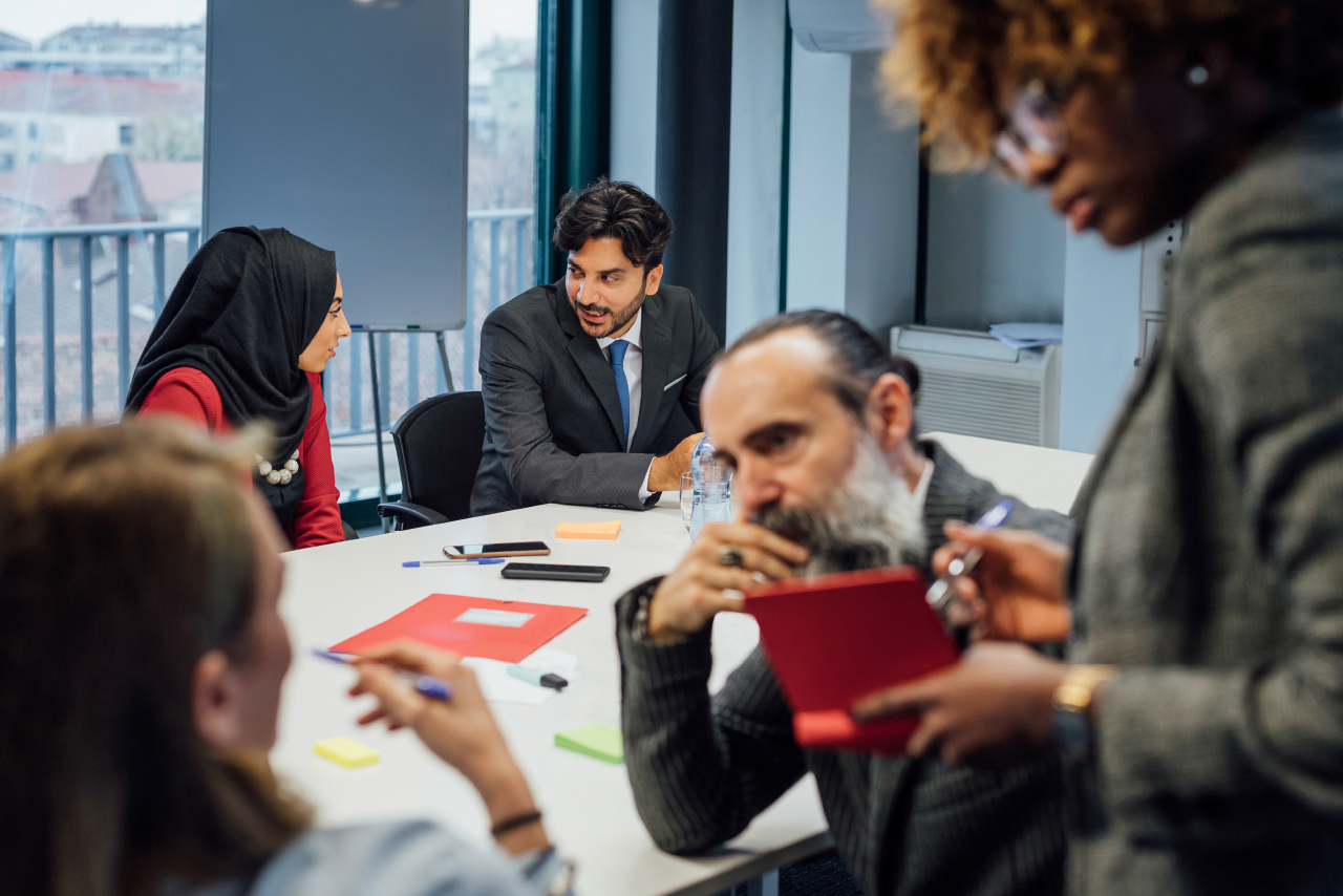 Participants in a meeting sit in a room and exchange ideas.