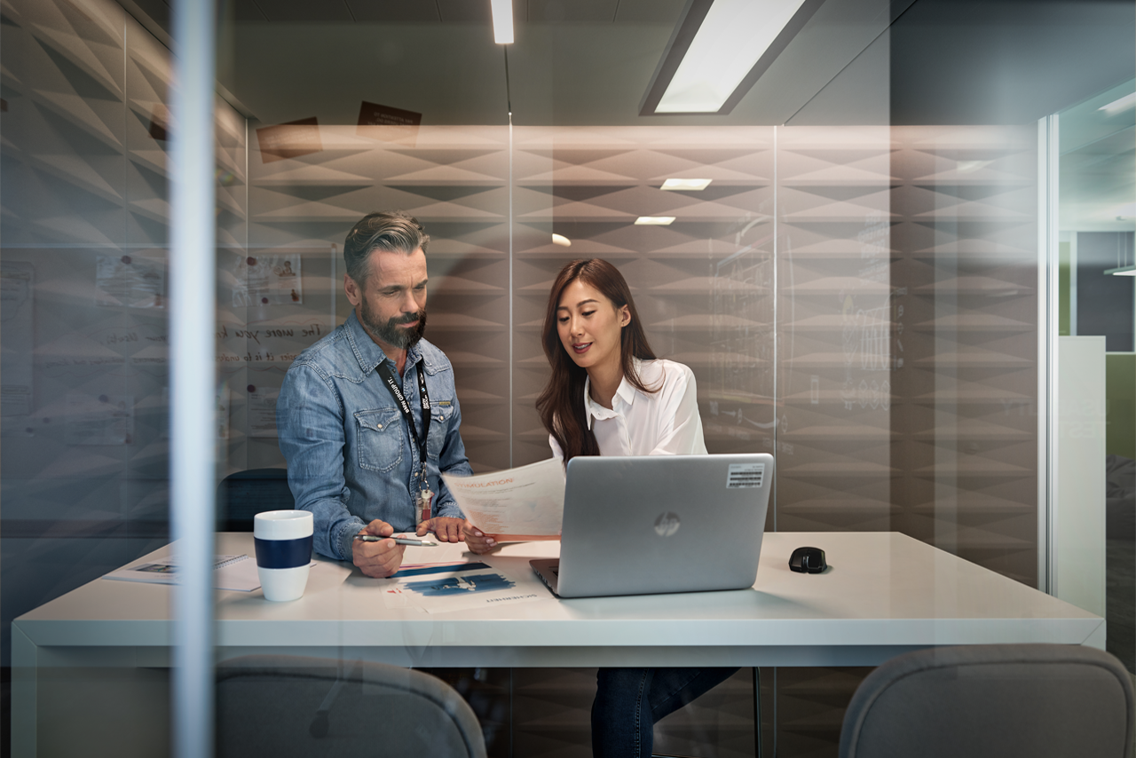 A man and a woman are sitting at a table with a laptop and talking.