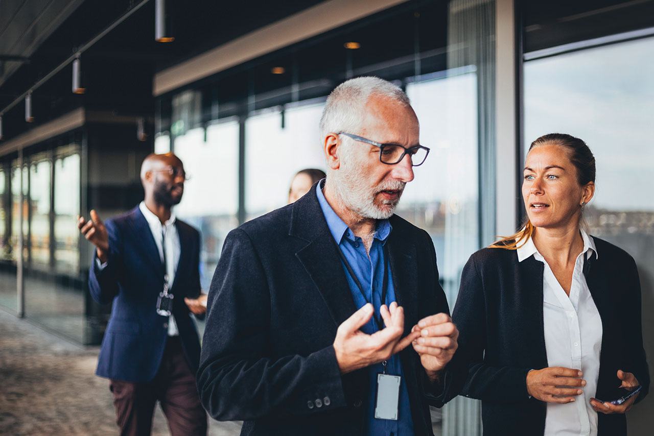 Two businesspeople are talking in front of a glass facade.